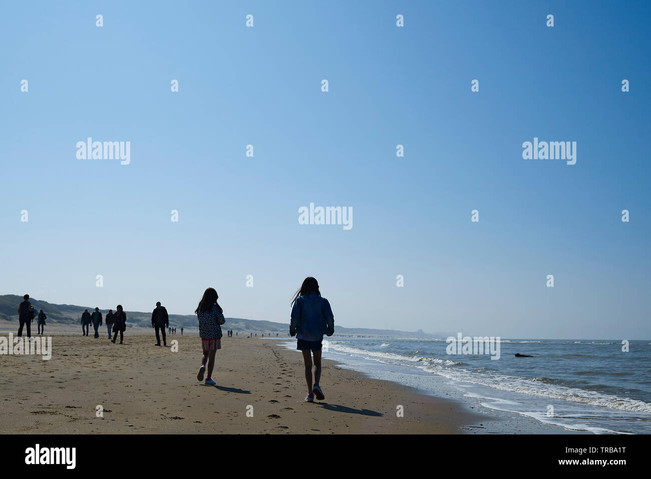 Groups of people enjoying a walk along the beach in bright srping