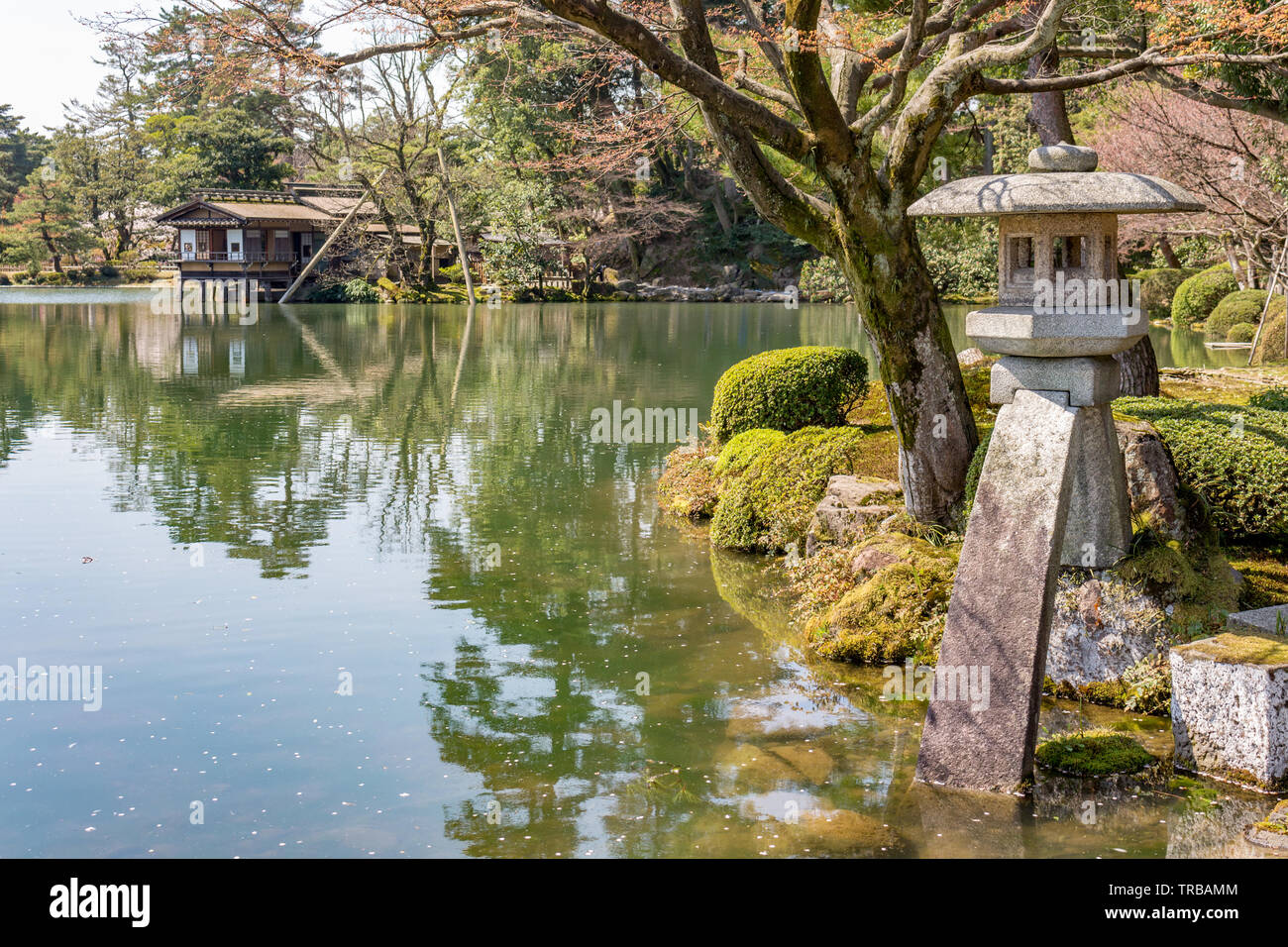 Stone Kotoji-toro lantern, teahouses, and trees reflected in Kasumi pond water, Kenrokuen gardens. Kanazawa, Ishikawa Prefecture, Western Japan. Kenro Stock Photo