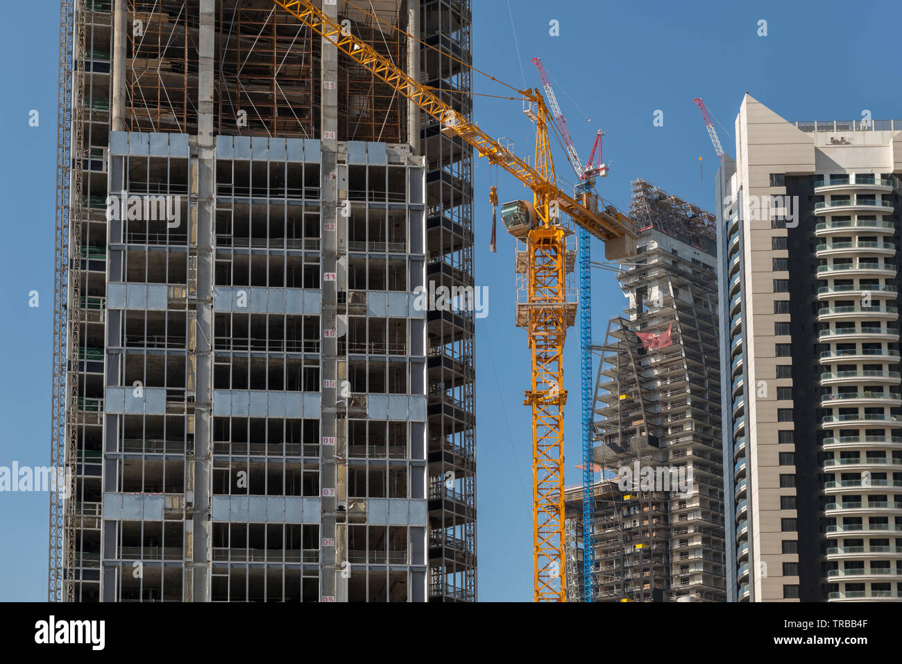 A yellow crane stands on a construction site where several skyscrapers are being built. Stock Photo