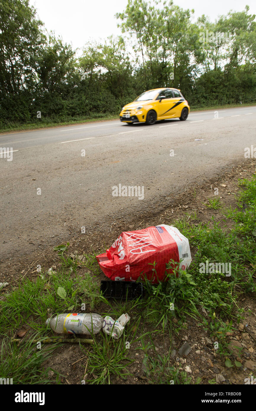 A car passing a lay-by in the countryside in which a bag of rubbish has been previously dumped. North Dorset England UK GB Stock Photo
