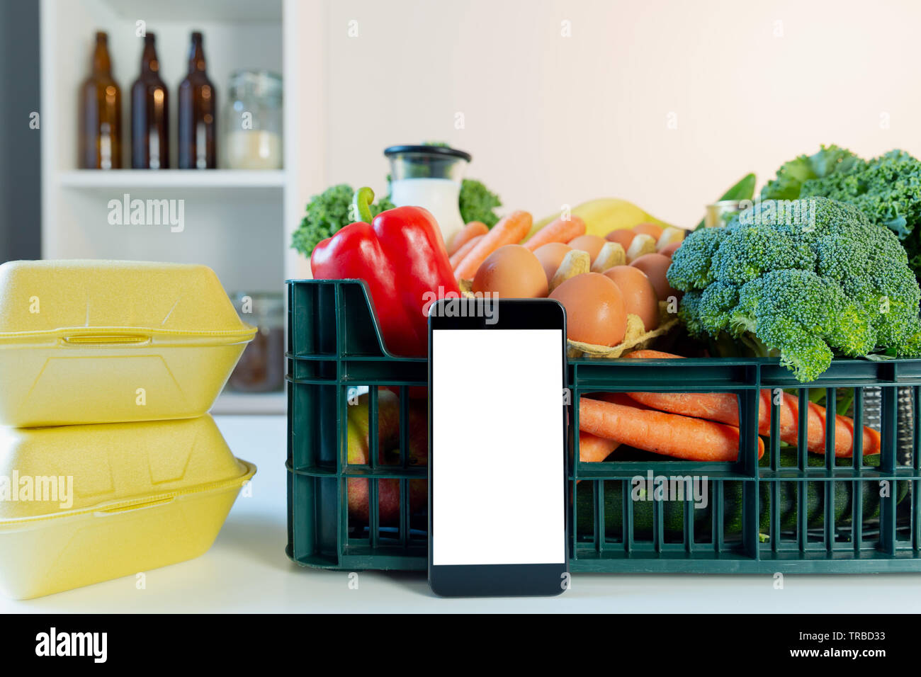 Food delivery service - smartphone in front of the box of groceries Stock Photo