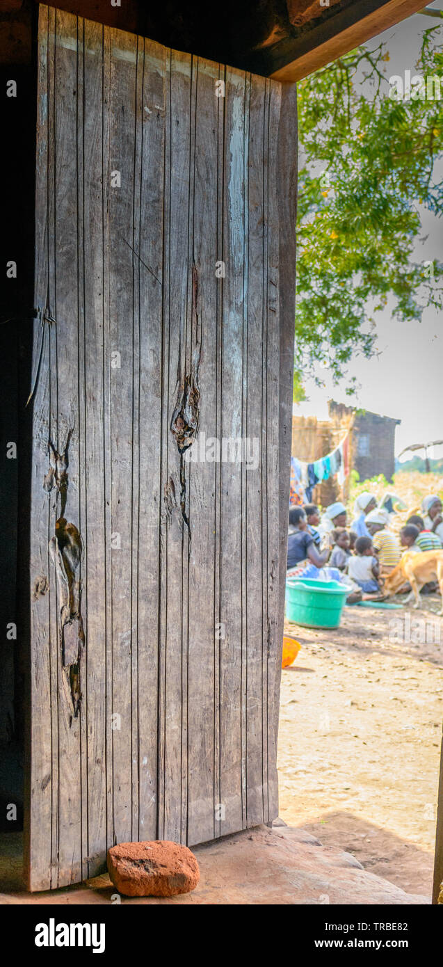 a wooden door of a house in a village of Malawi propped open by a home made brick Stock Photo
