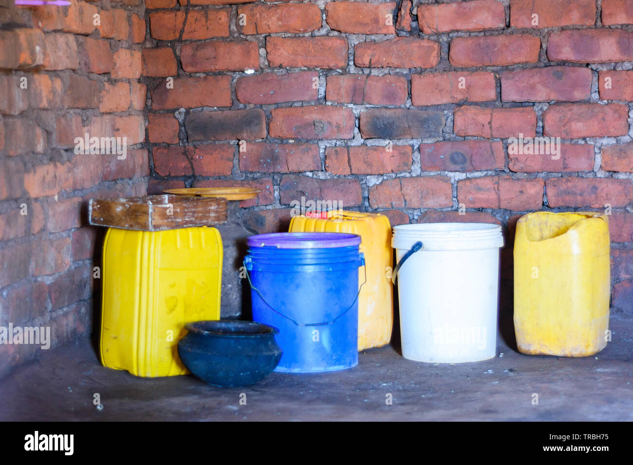 plastic containers recycled so that they can be used to store water, maize flour and food in a house in a Malawian village Stock Photo