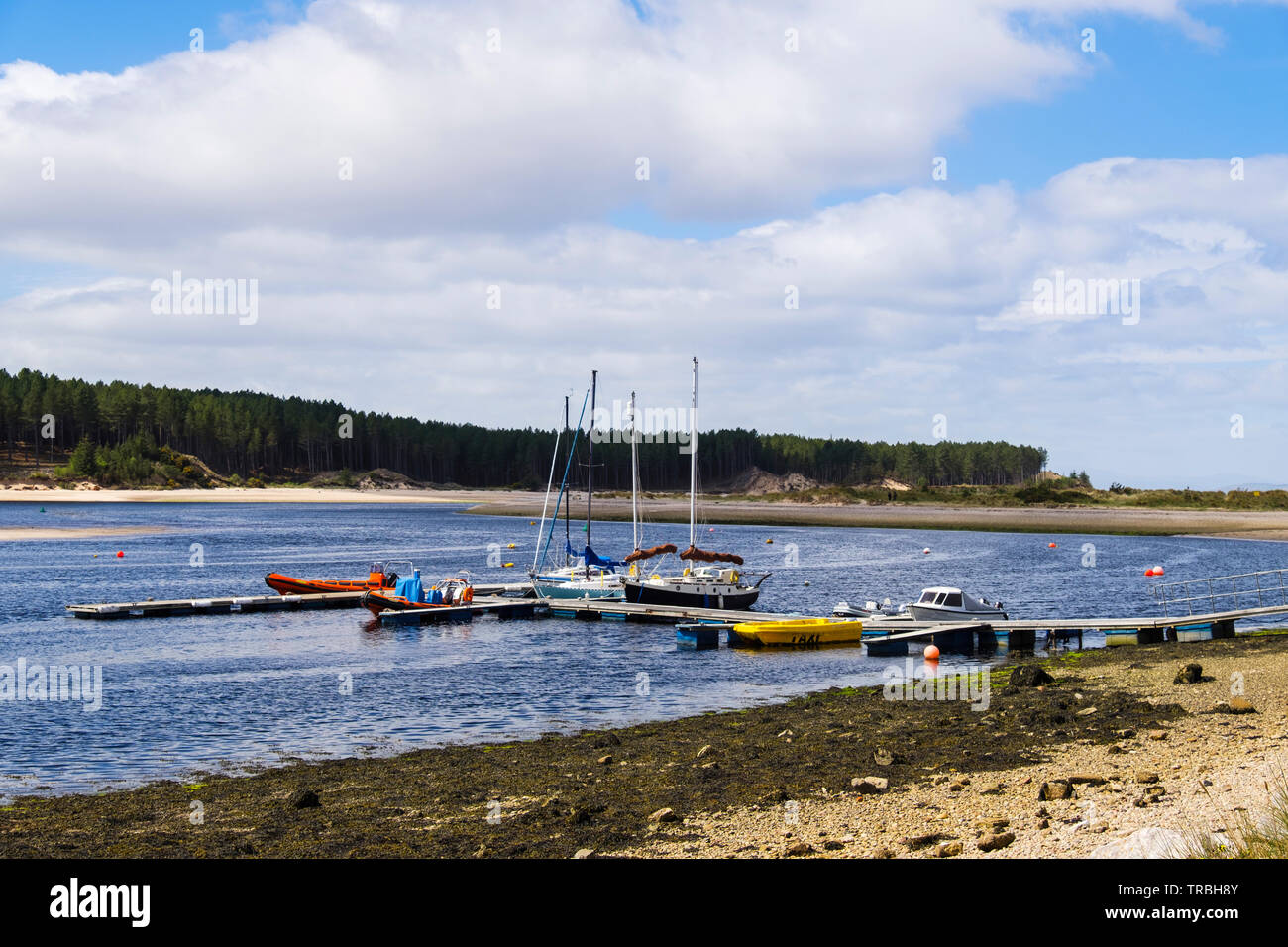 Boats moored by jetty in tidal river estuary in Findhorn Bay harbour. Findhorn, Moray, Scotland, UK, Britain Stock Photo