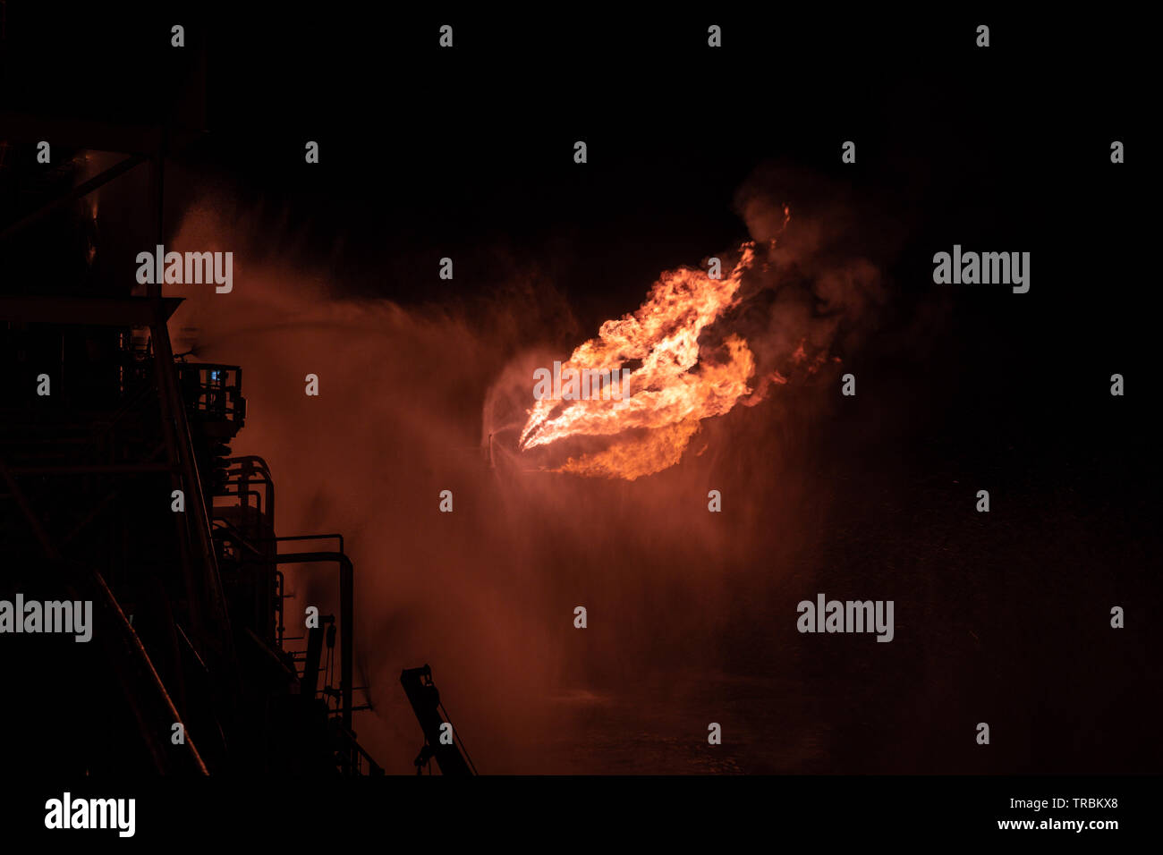 Well testing operation (flaring) of an oil and gas drilling rig. Burning huge gas flame controlled by the deluge system Stock Photo