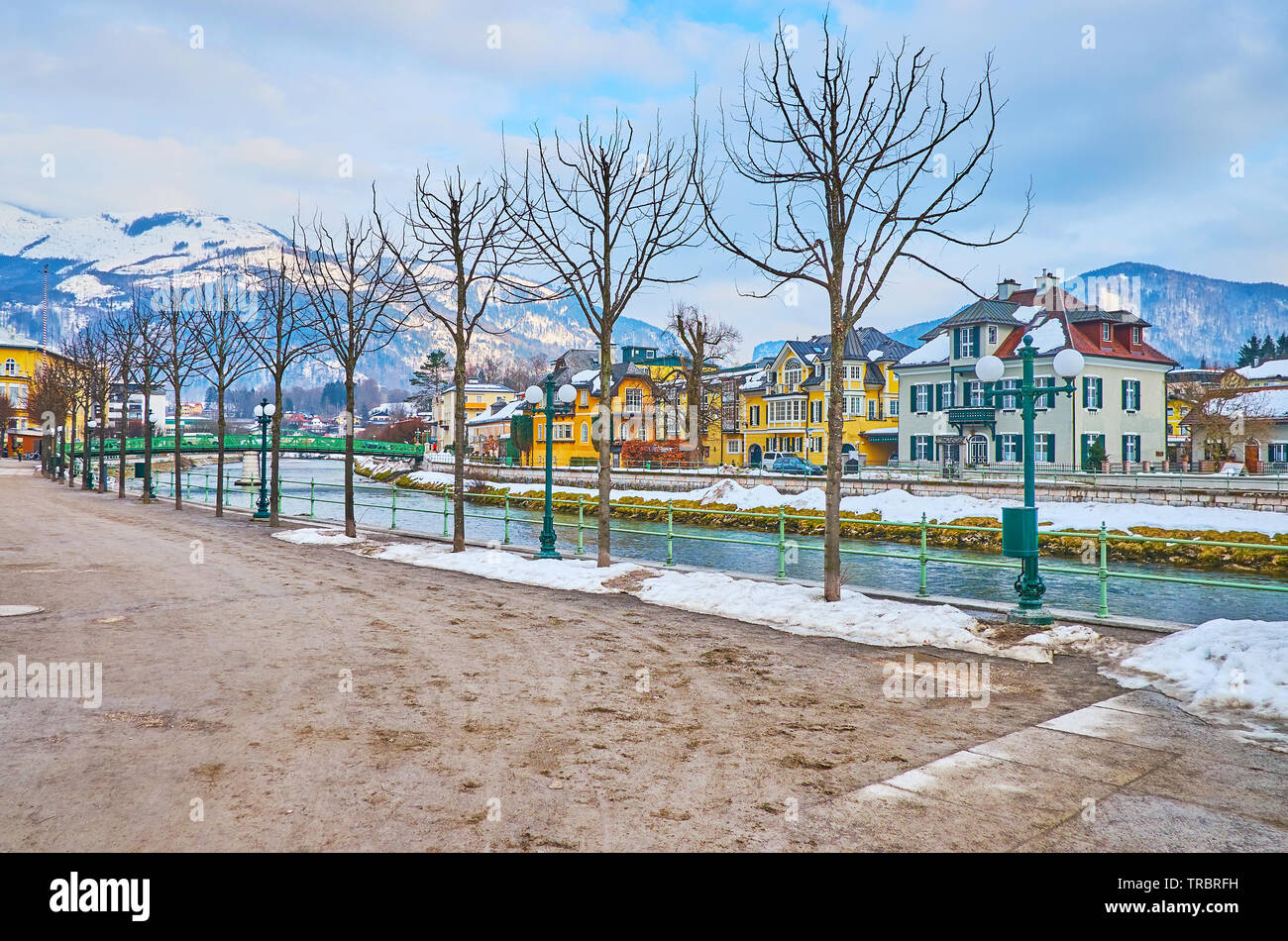The winter Esplanade embankment of Traun river with a line of young trees, retro streetlights and nice views, Bad Ischl, Salzkammergut, Austria Stock Photo