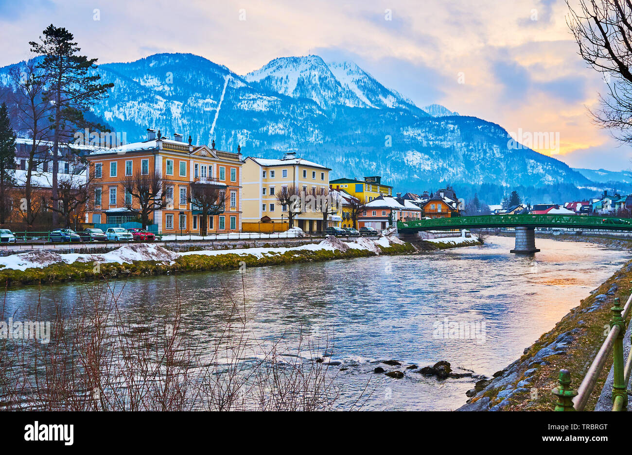 Bright sunset sky reflects in waters of Traun River, flowing along the old town with a view on its villas and Mount Katrin, Bad Ischl, Austria Stock Photo