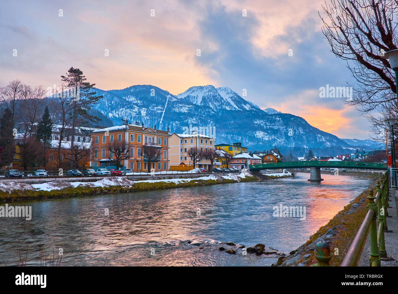 Watch the sunset above the snowy Katrin Mount from the bank of Traun river with a view on center of small town in Salzkammergut, Bad Ischl, Austria. Stock Photo