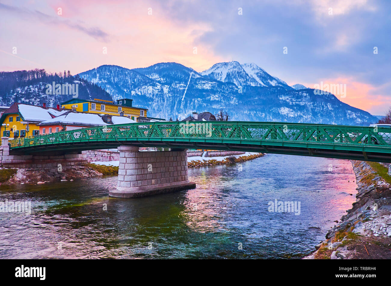 Enjoy the evening walk in Bad Ischl with a view on Kaiserin Elizabeth bridge, Mount Katrin and bright sunset sky, reflecting in waters of Traun river, Stock Photo