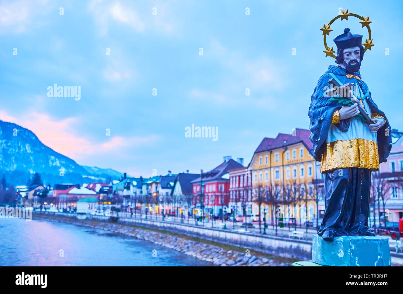 The beautiful statue of St Johannes Nepomuk with a view on evening town, sunset sky and Traun river, Bad Ischl, Salzkammergut, Austria Stock Photo