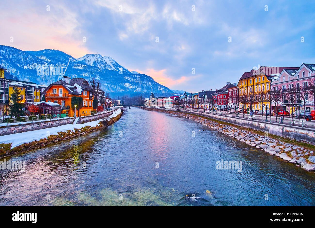 BAD ISCHL, AUSTRIA - FEBRUARY 20, 2019: The cloudy sunset sky above the Alps with traditional Salzkammergut housing on the banks of Traun river on the Stock Photo