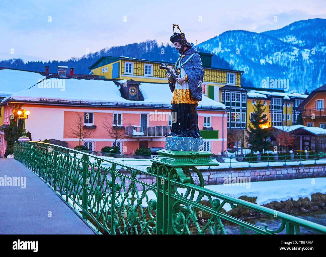 The evening walk along historic Kaiserin Elizabeth bridge with a view on statue of Johannes Nepomuk, old townhouses and snowy mountains on the backgro Stock Photo