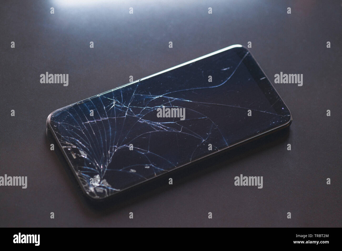 Smartphone with broken touchscreen screen on black table desktop Stock Photo
