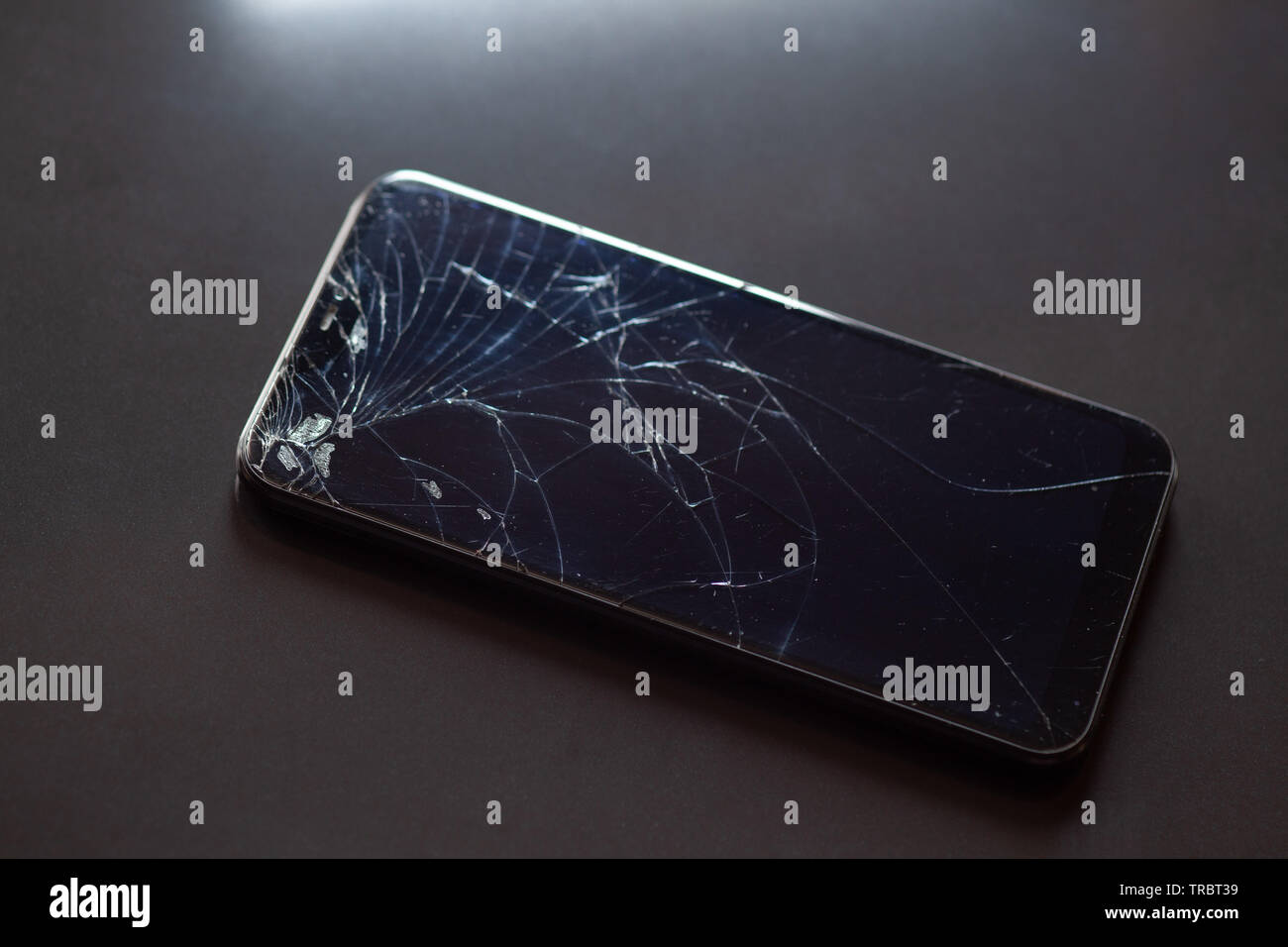 Smartphone with broken touchscreen screen on black desktop Stock Photo