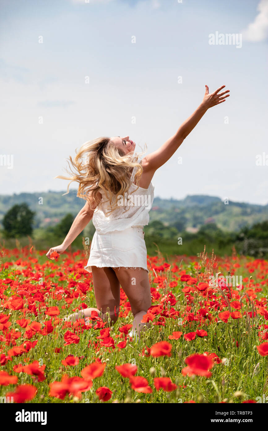 Young beautiful girl younping in the poppy field Stock Photo