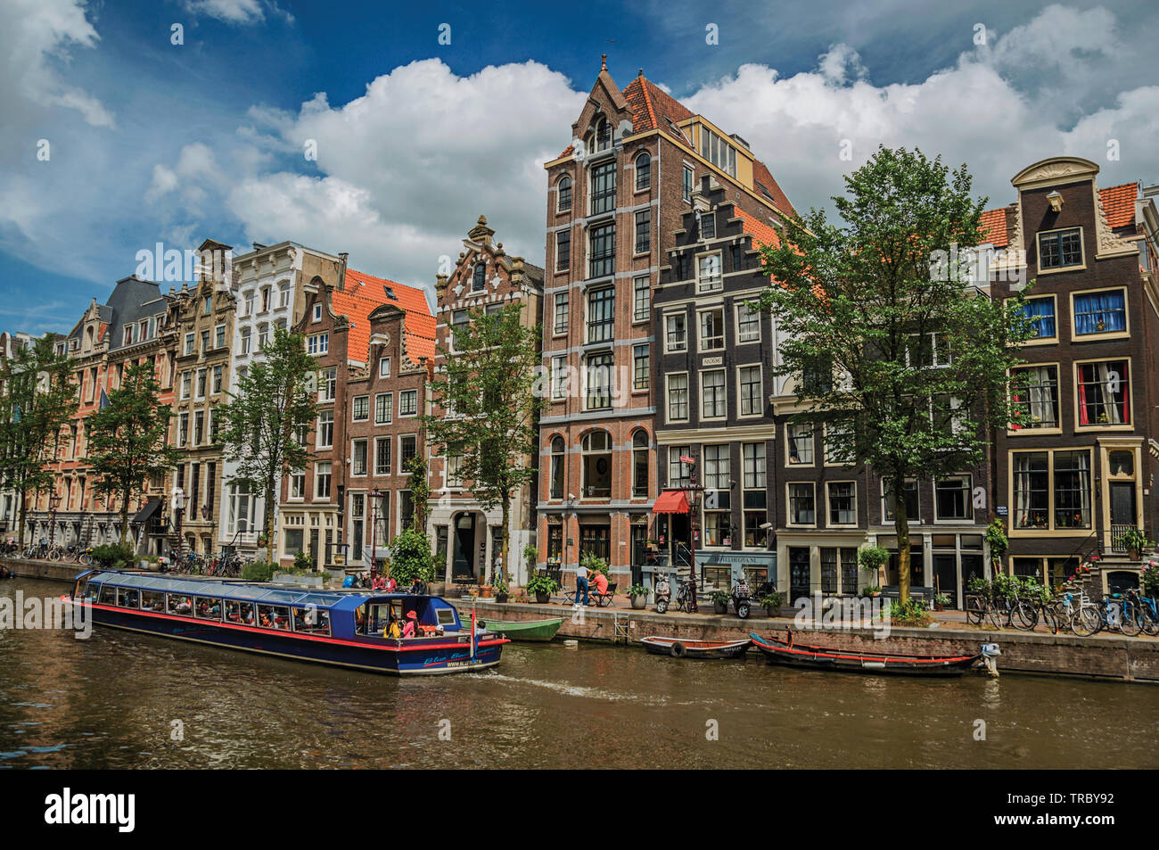 Canal with old brick buildings, boats and sunny blue sky in Amsterdam. City with huge cultural activity, canals and bridges in Netherlands. Stock Photo