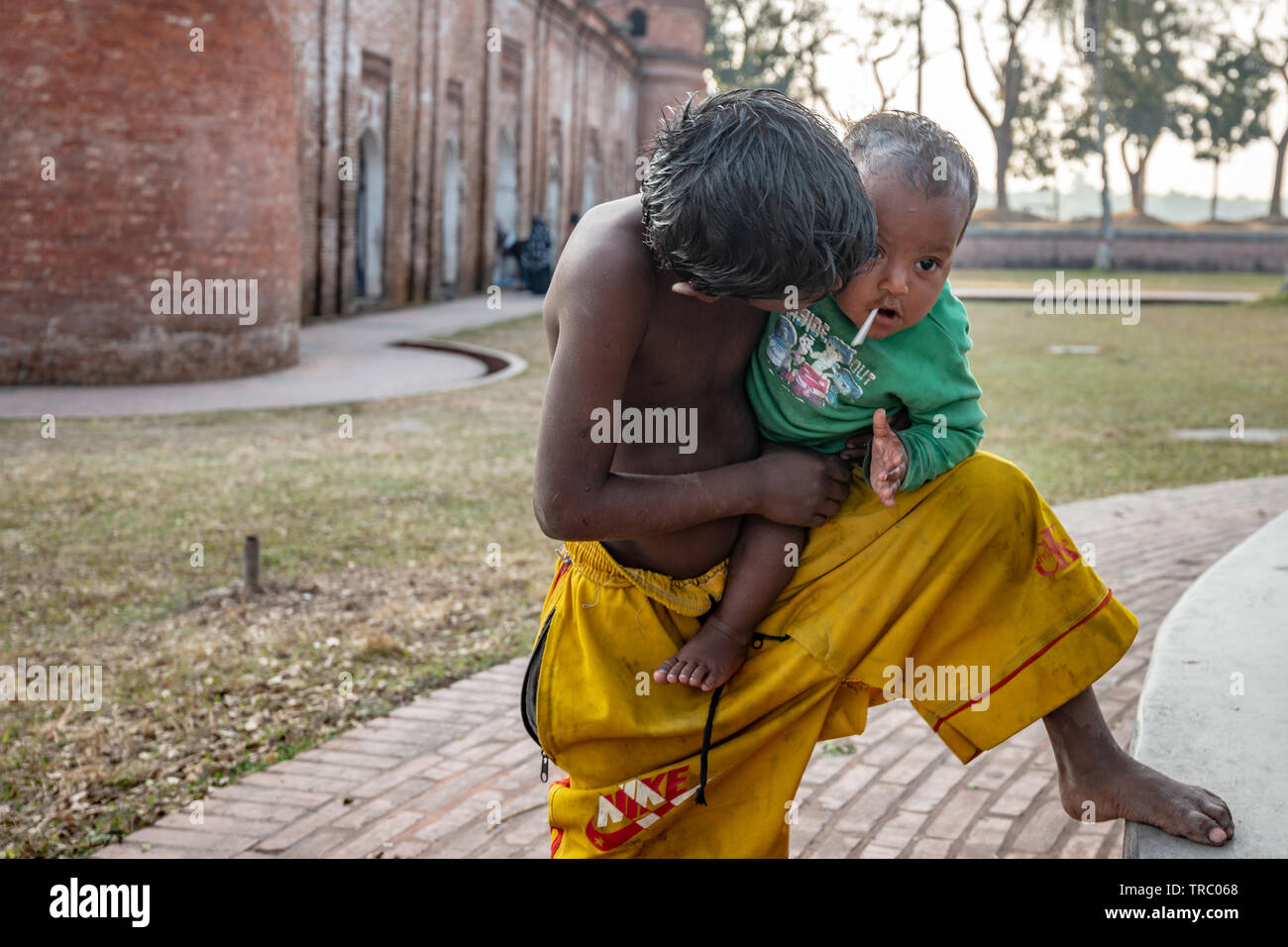 Young boy babysitting his baby brother at Shait Gumbad Mosque, Bangladesh Stock Photo