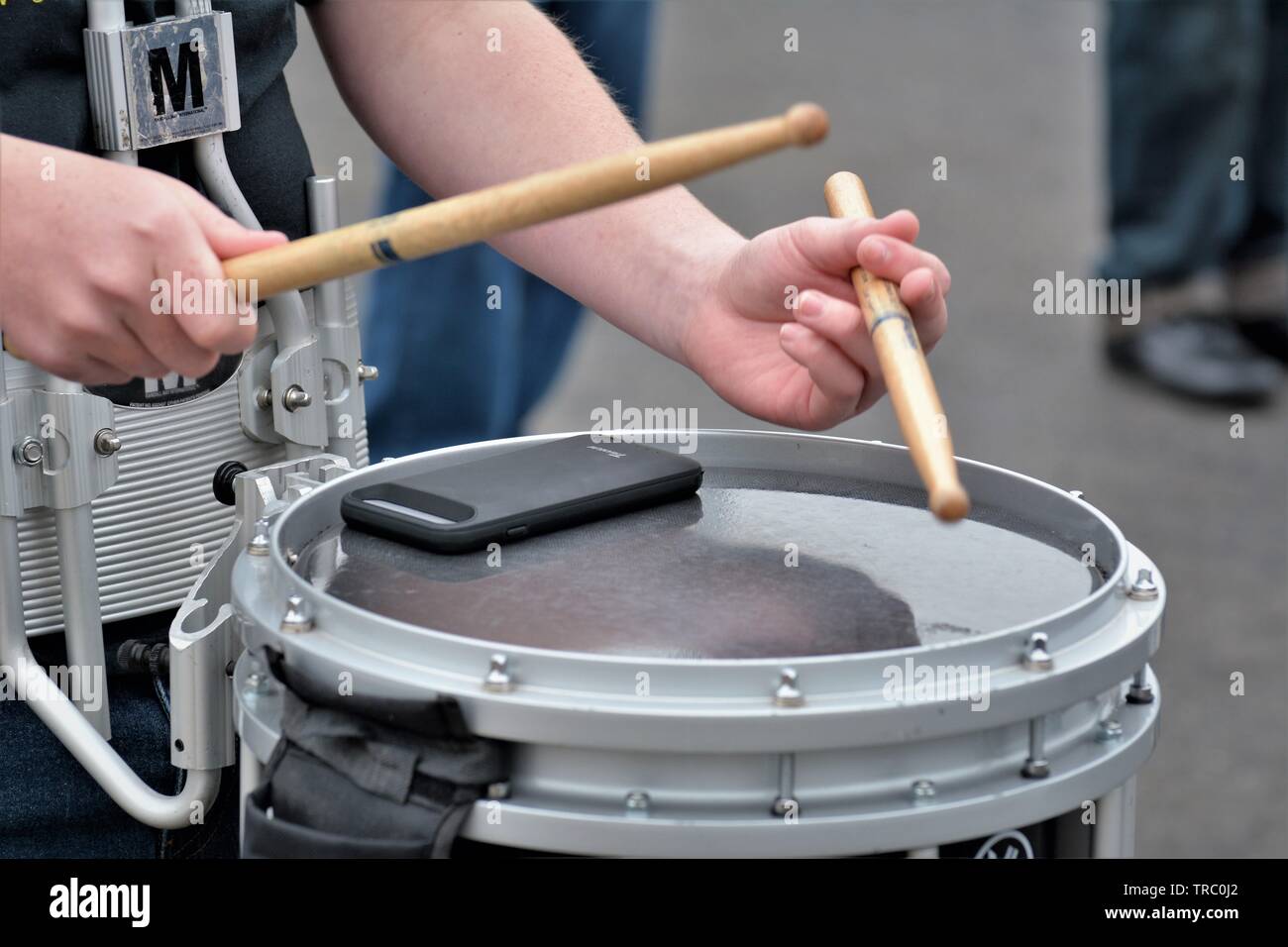 A drummer in a real high school band with his cell phone on the drum as he plays vibration, connected Stock Photo