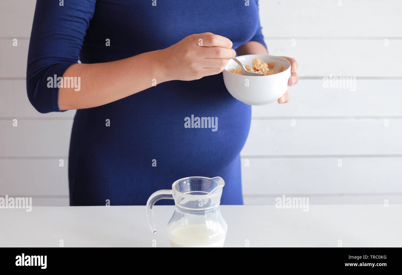 pregnant woman eat wholegrain cereals with fresh milk Stock Photo