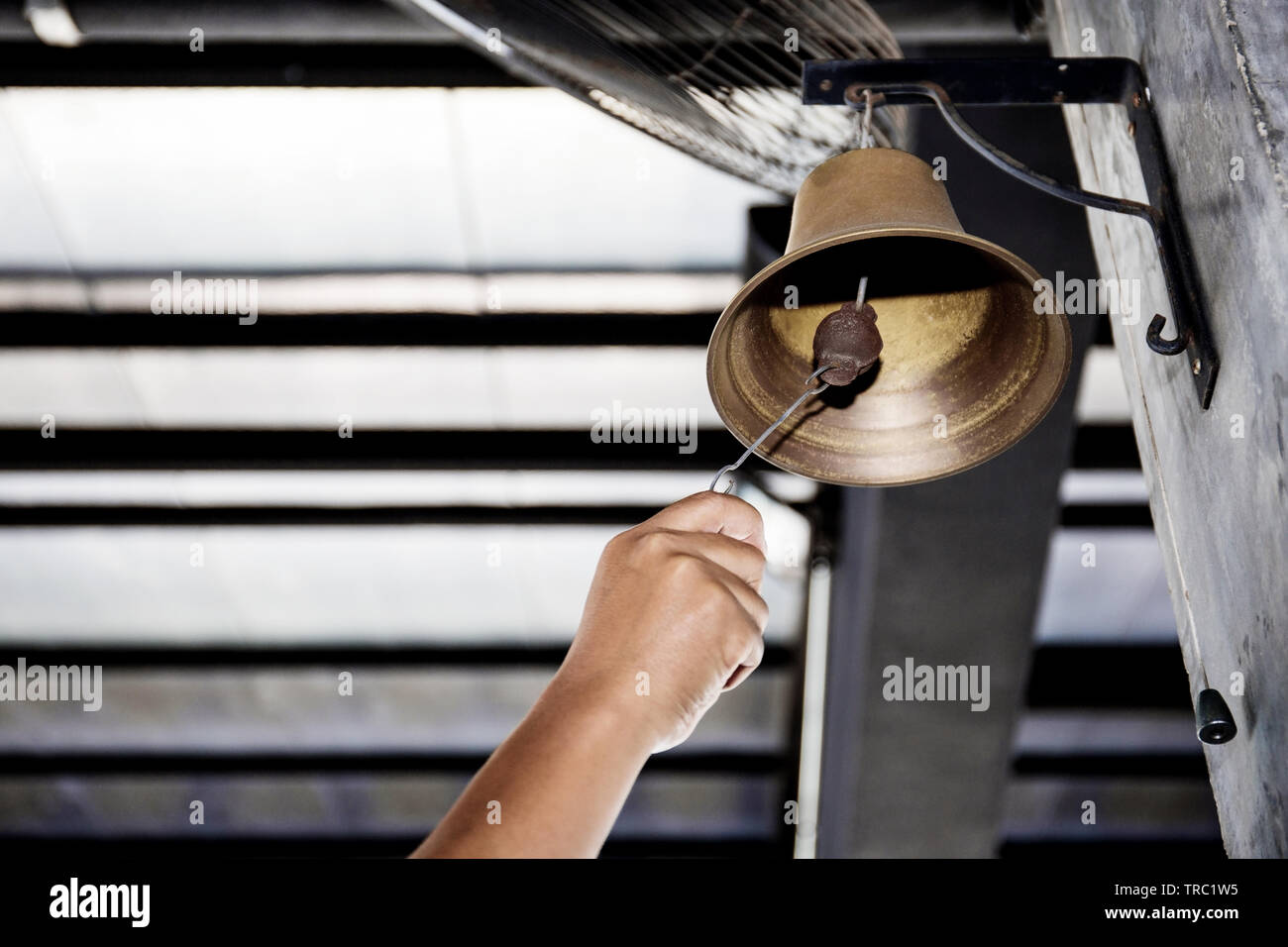 Hand is shaking bell hanging on pole of the boxing stadium Stock Photo