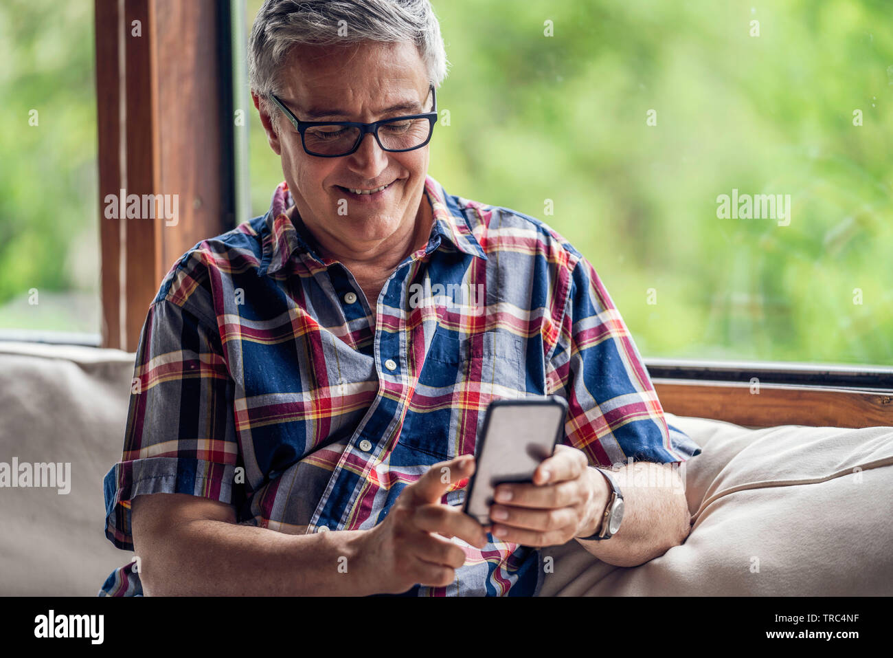 Smiling mature man using smartphone Stock Photo