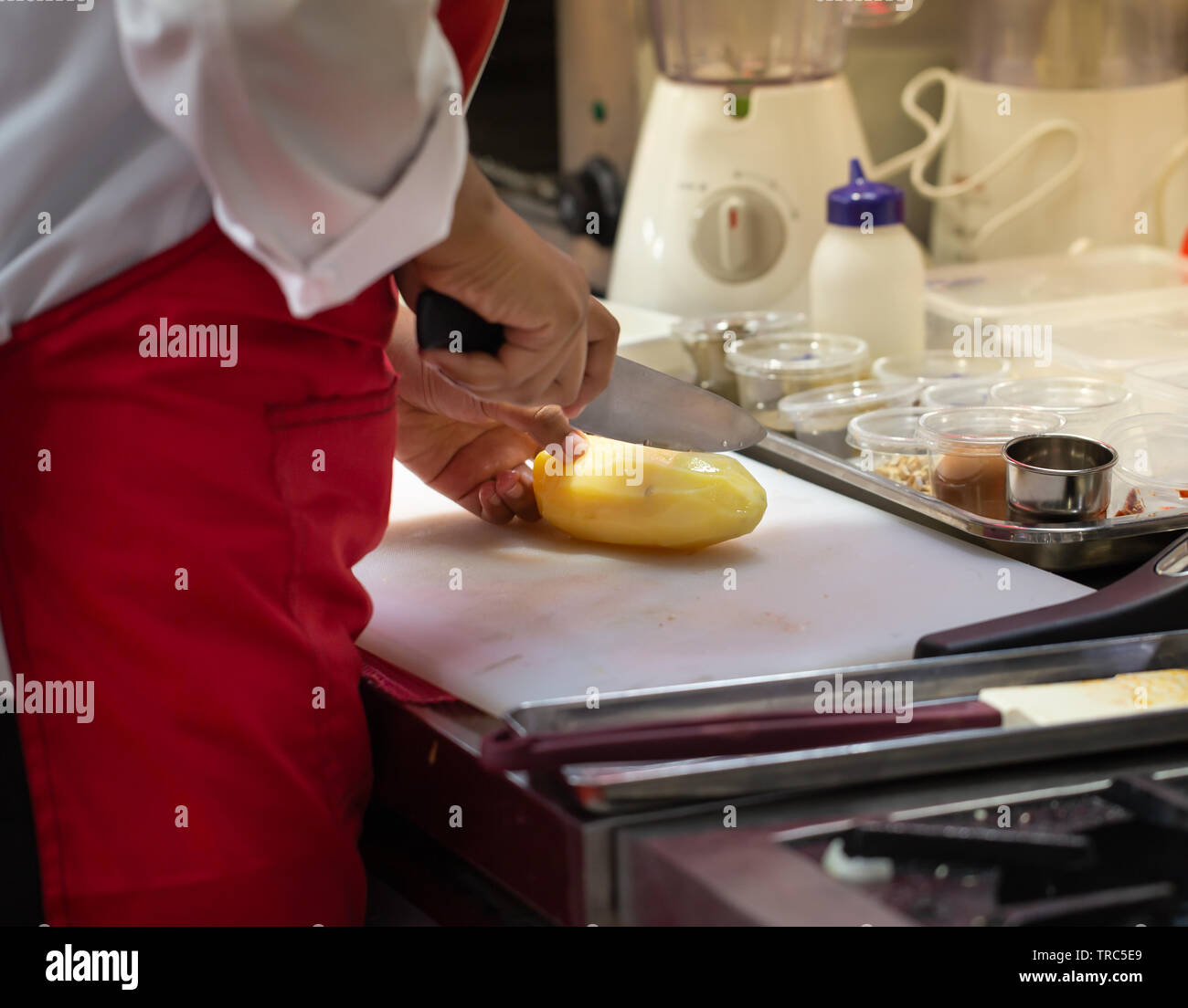 Chef Cutting Raw Fresh Potato On A Plastic Cutting Board Stock