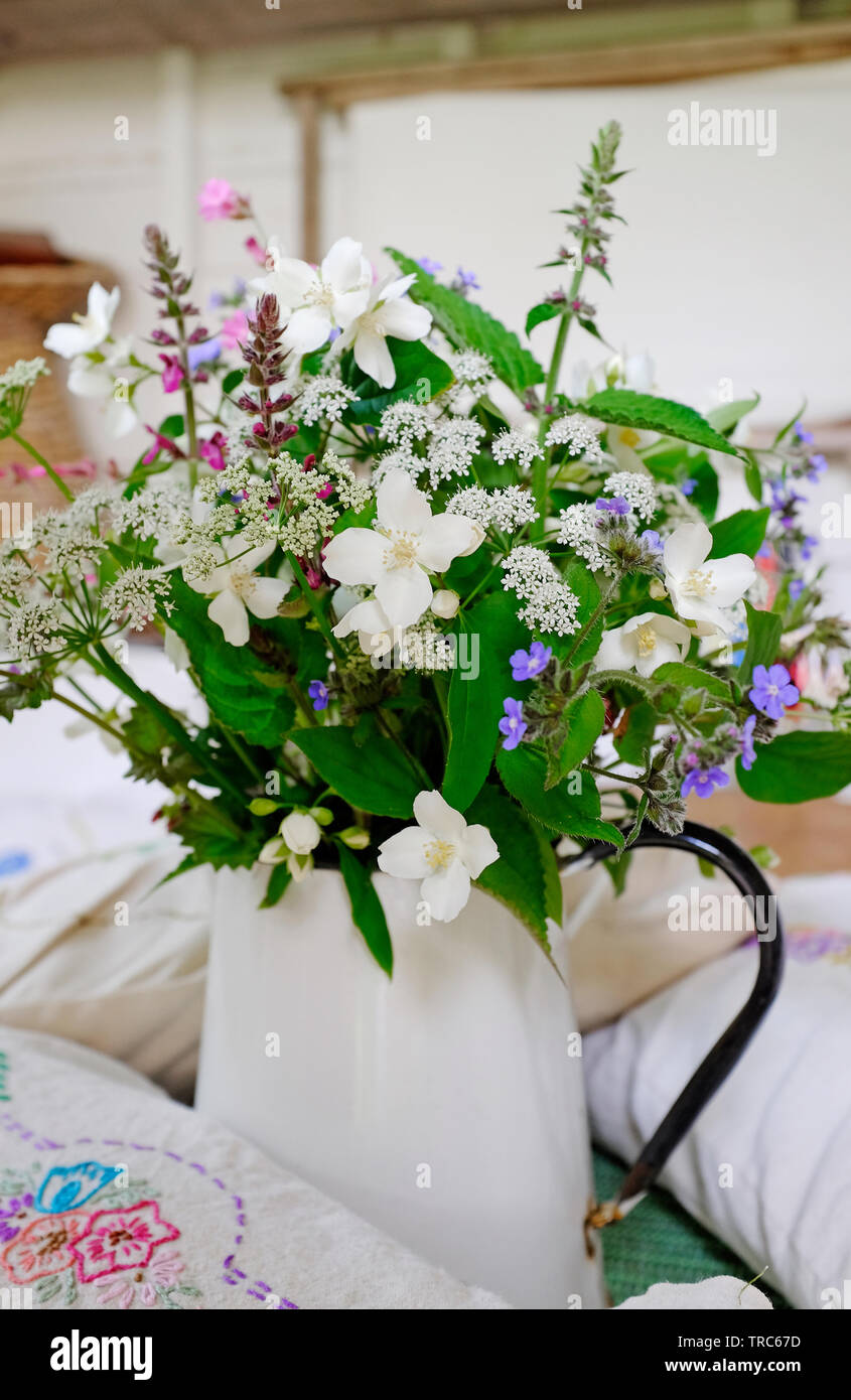 mixed wildflowers in white metal jug Stock Photo