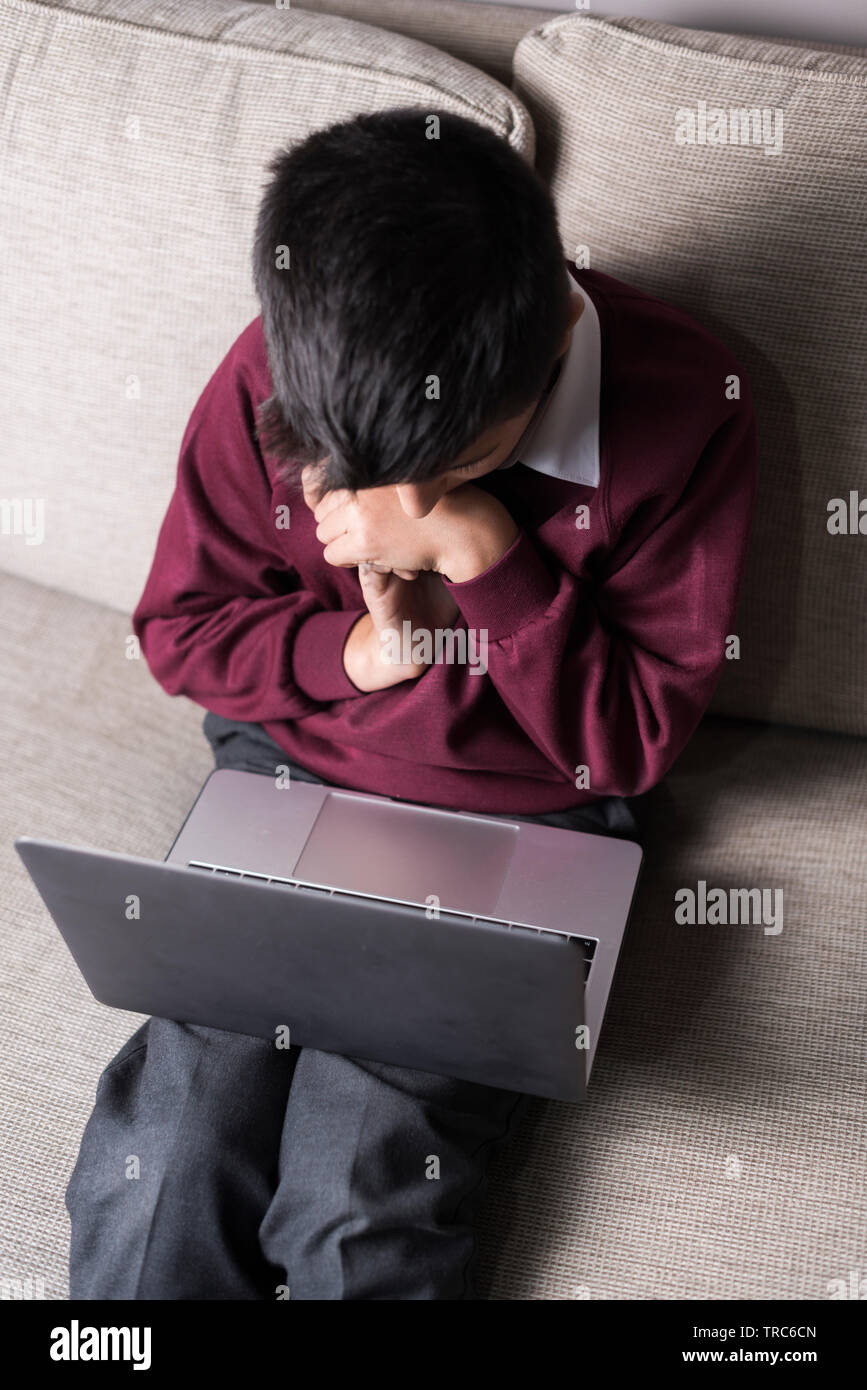 UK, 11 years old primary schoolboy in school uniform  on laptop computer- top view. Stock Photo