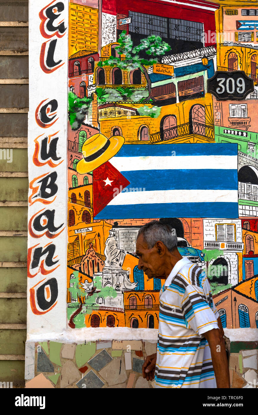 Cuban man walks by artwork at the entrance to the El Cubano Restaurant at Murallo No.309,  Old Town, Havana, Cuba, Caribbean Stock Photo