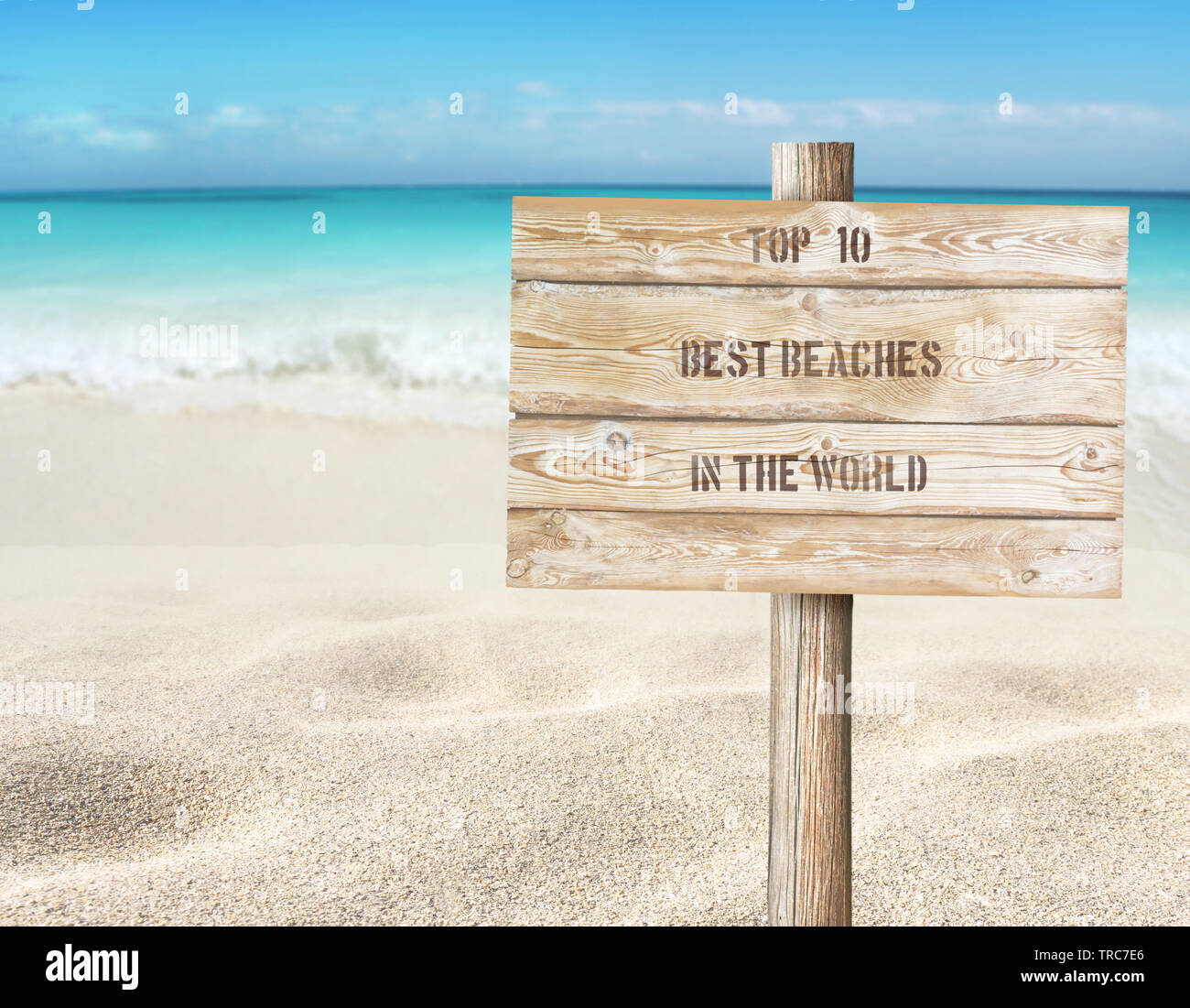 Top ten beaches in the world message on the wooden planks sign board on the beach blurred background.  Tropical island paradise. Sandy shore washing b Stock Photo