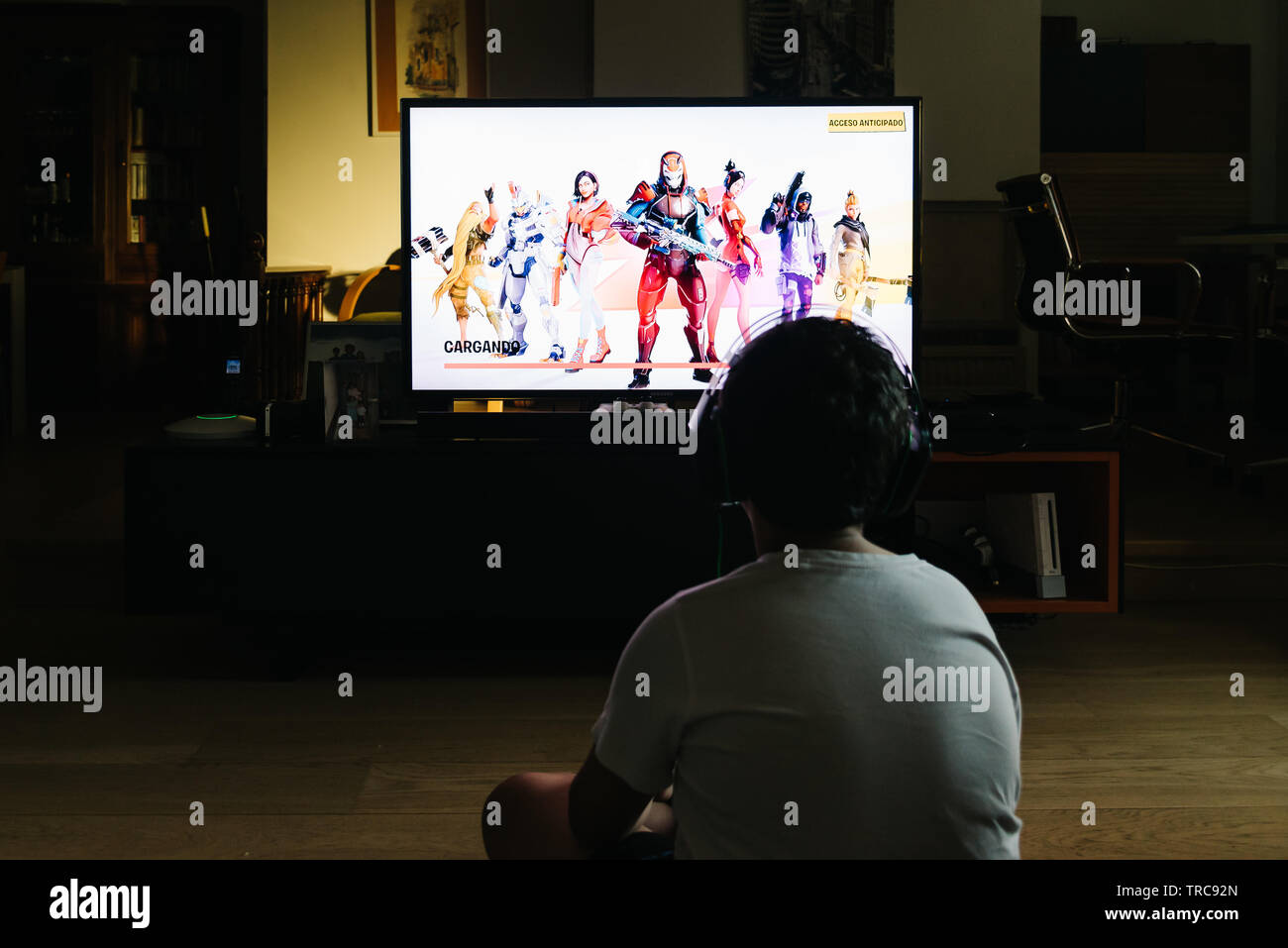 Madrid, Spain - May 29, 2019: Teenager playing Fortnite video game withn Playstation on TV. Fortnite is an online multiplayer video game developed by Stock Photo