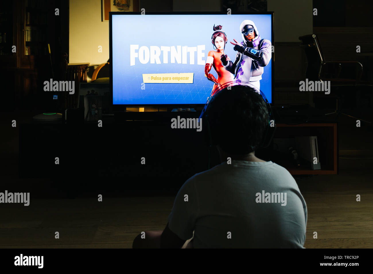 Madrid, Spain - May 29, 2019: Teenager playing Fortnite video game withn Playstation on TV. Fortnite is an online multiplayer video game developed by Stock Photo