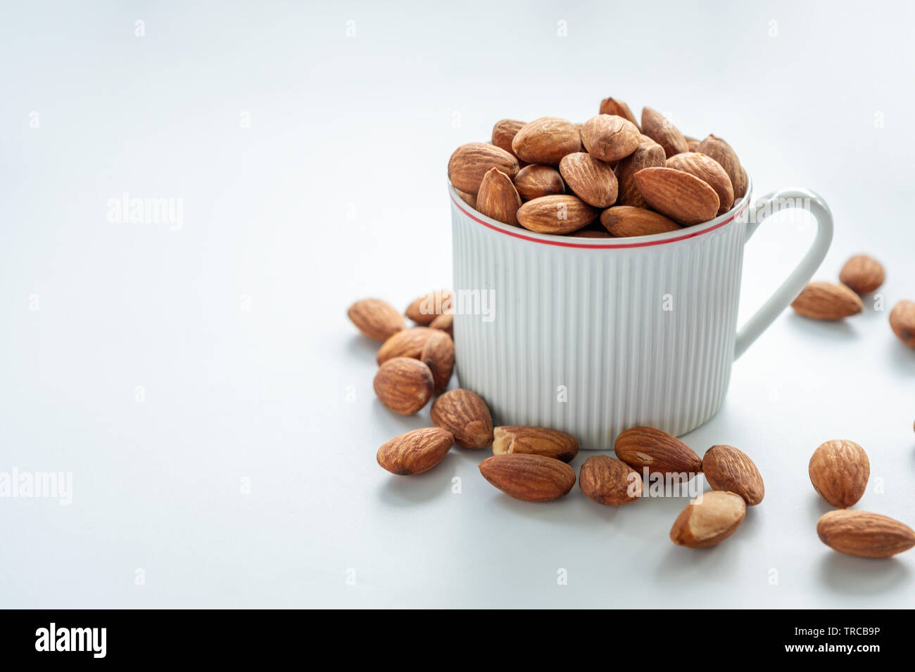 Almonds in white cup on white background Stock Photo