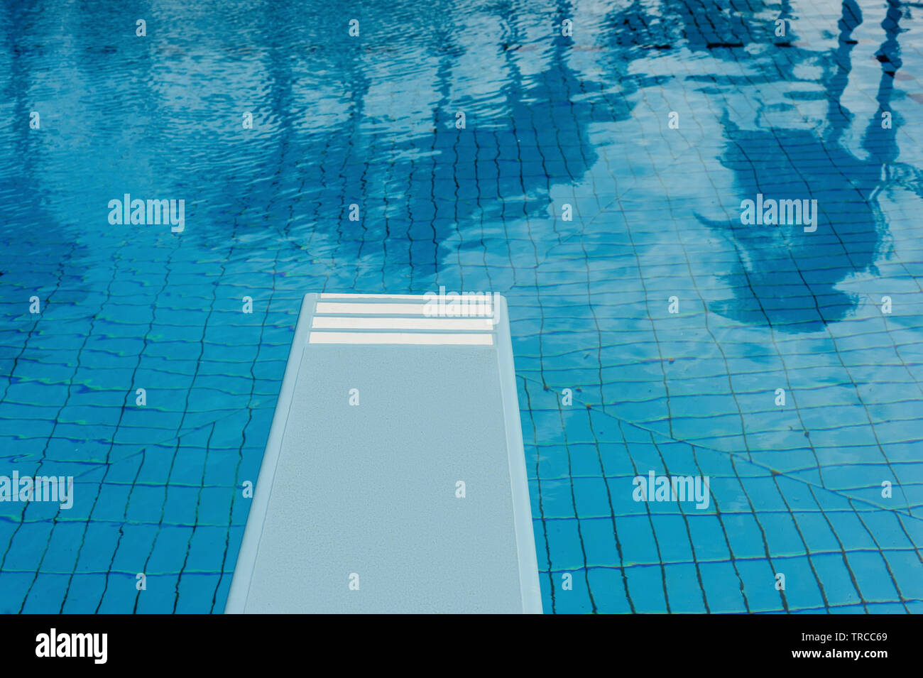 Crystal clear swimming pool with refreshing blue water, springboard and ...