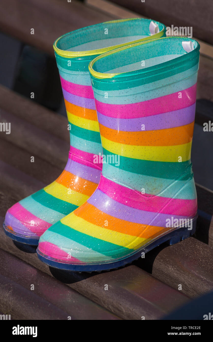 Pair of children's colourful striped wellington boots, wellies, on bench at Weymouth, Dorset UK in June Stock Photo