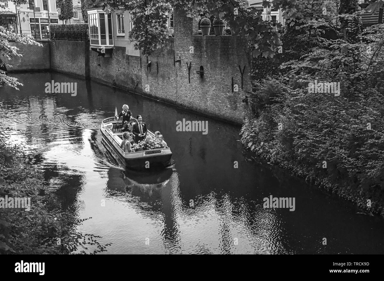 Boat with people navigating the canal with lush vegetation in s-Hertogenbosch. Gracious historical city with vibrant cultural life in Netherlands. Stock Photo