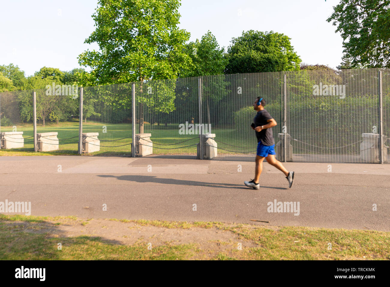 Jogger running past temporary fencing. Security around Winfield House, Regent's Park, London, UK for the State Visit of US President Donald Trump. Stock Photo