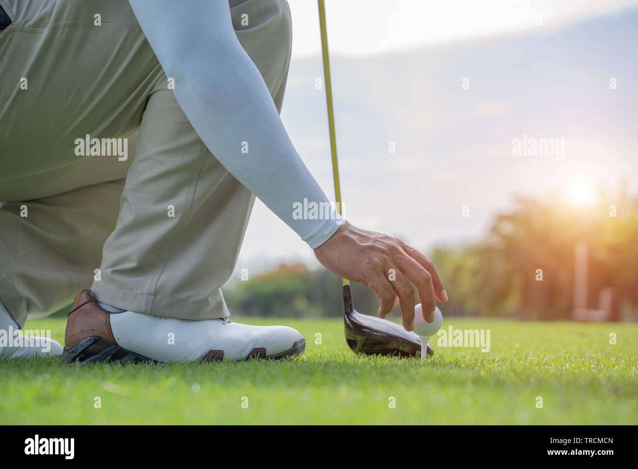 Man hand putting golf ball on tee in golf course - Image Stock Photo