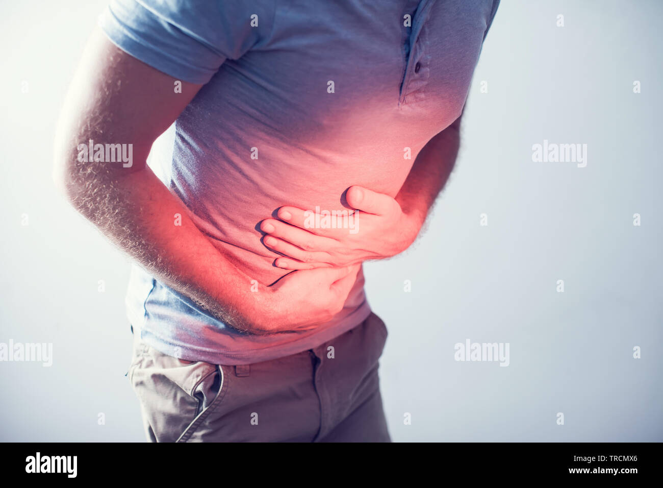 People, healthcare and problem concept - unhappy man suffering from stomach ache over gray background Stock Photo