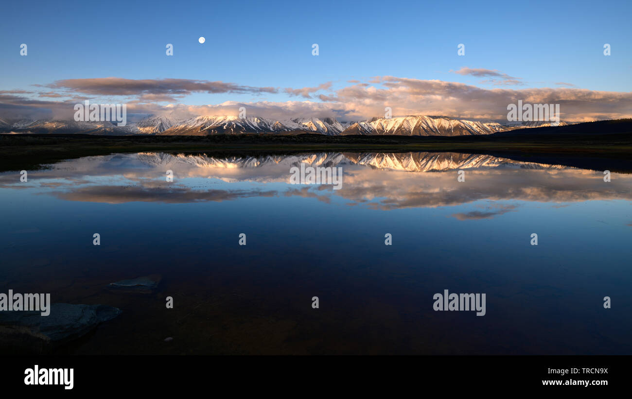 Moonset over Laurel Mountain and Mt. Morrison during sunrise near the town of Mammoth Lakes, in the sierra mountains of California as seen from Long V Stock Photo