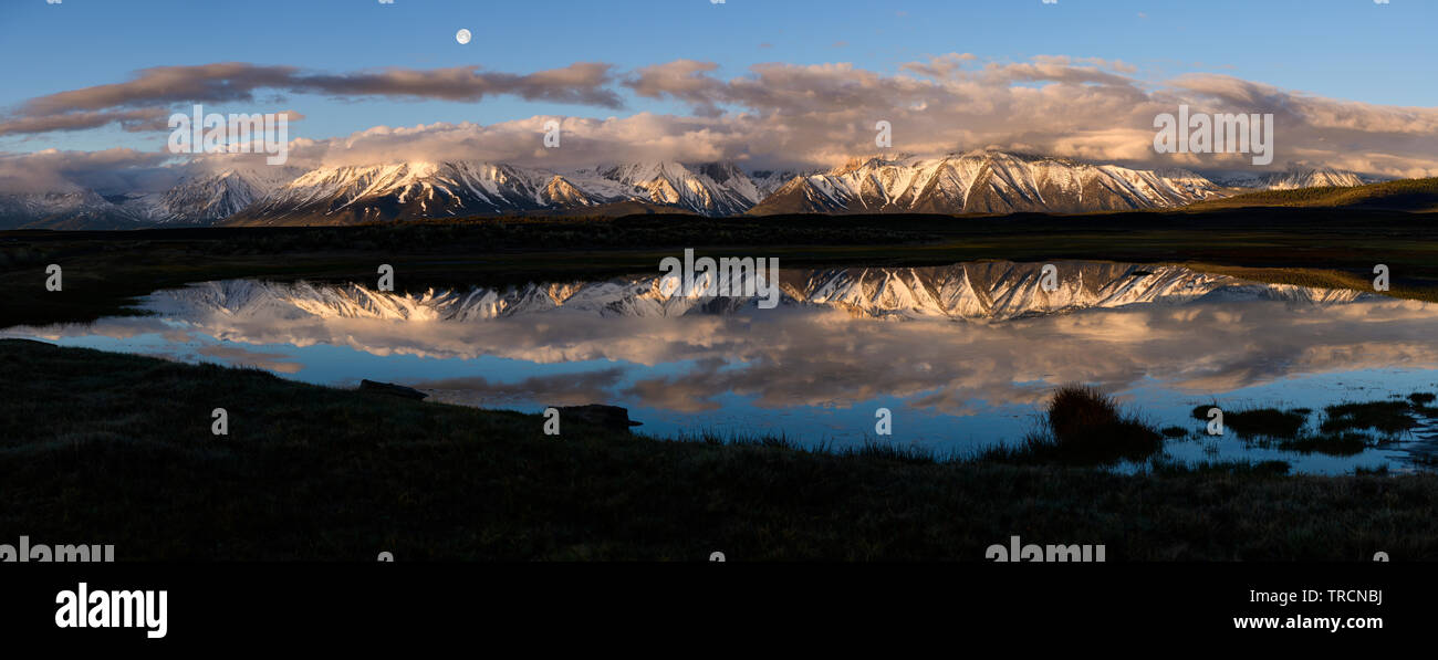 Moonset over Laurel Mountain and Mt. Morrison during sunrise near the town of Mammoth Lakes, in the sierra mountains of California as seen from Long V Stock Photo