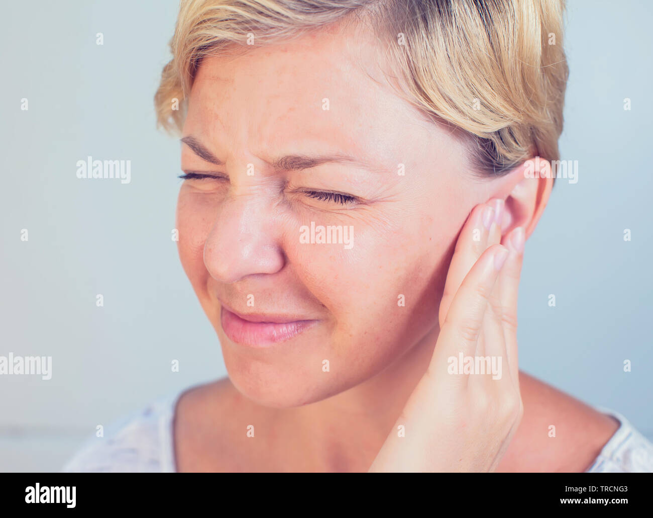 young female having ear pain touching her painful head earache Stock