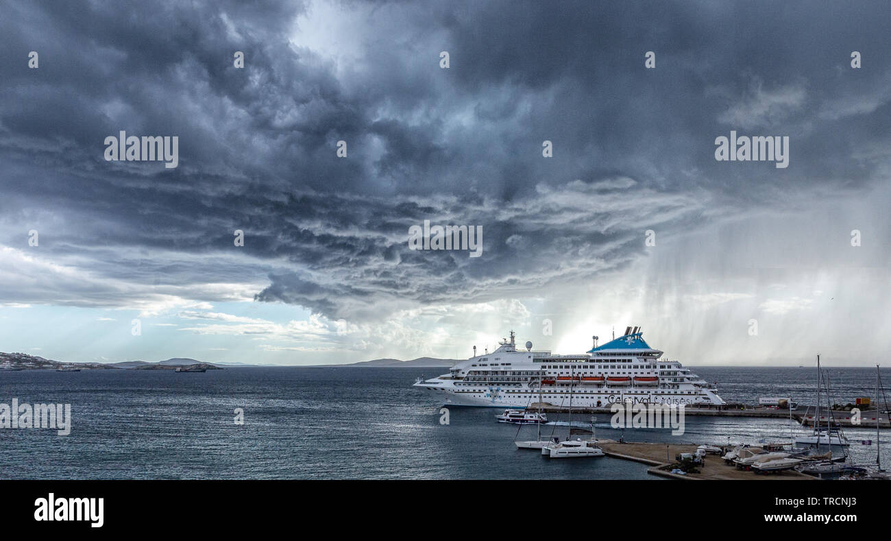 Mykonos, Greece - May 7, 2019:  A Celestyal Cruises ship waits out a storm at a port in Mykonos, Greece. Stock Photo