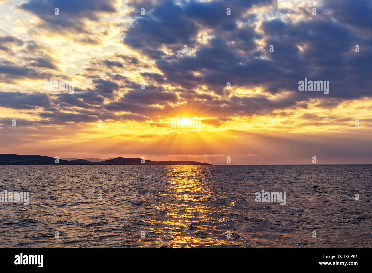 Colorful sunset with clouds on the Aegean sea, off the coast of Mykonos, Greece. Stock Photo