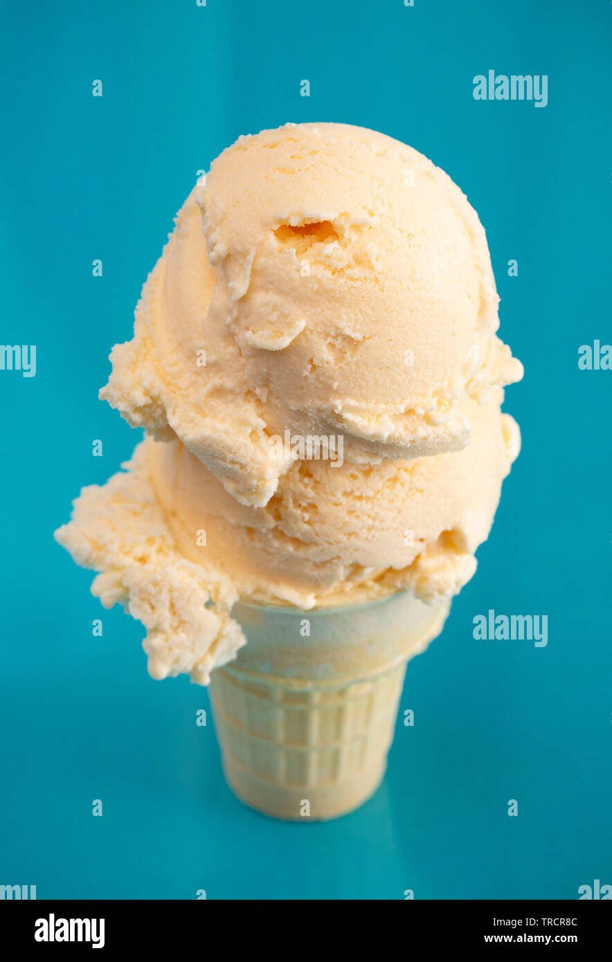 Double Scoop Vanilla Ice Cream Cone on a Blue Background Stock Photo
