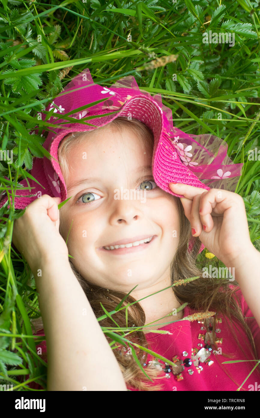 Happy beautiful little girl, outdoors relaxing on a field of daisies. Stock Photo
