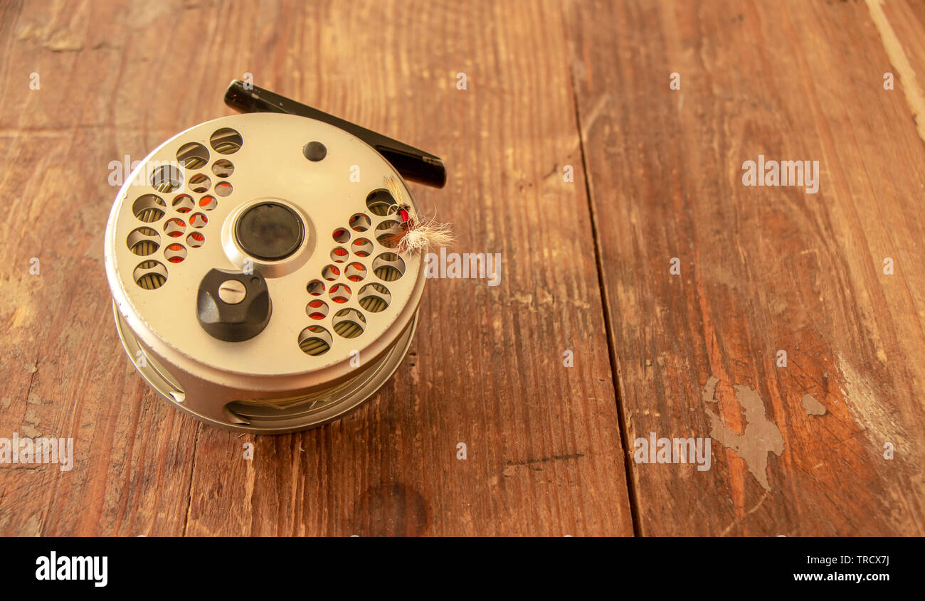 Weathered Fly Fishing Reel & Fly On Rustic reclaimed wood Table Stock Photo