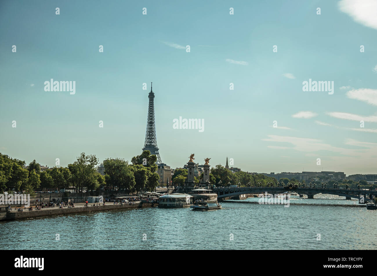 Seine River bank with boats, trees, bridge and the Eiffel Tower at
