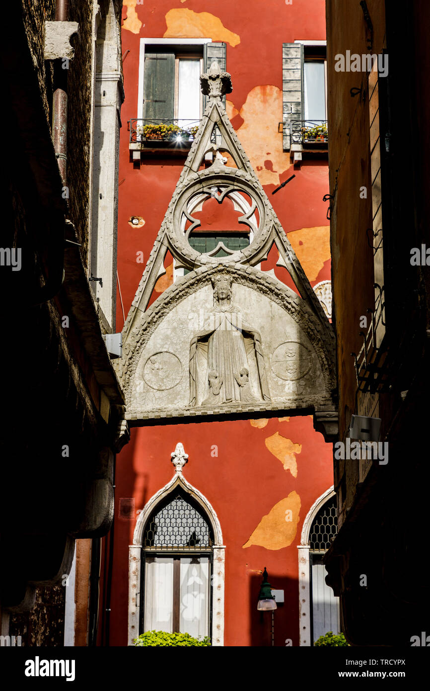A remnant from a religious structure spans a walkway in Venice Italy. Stock Photo