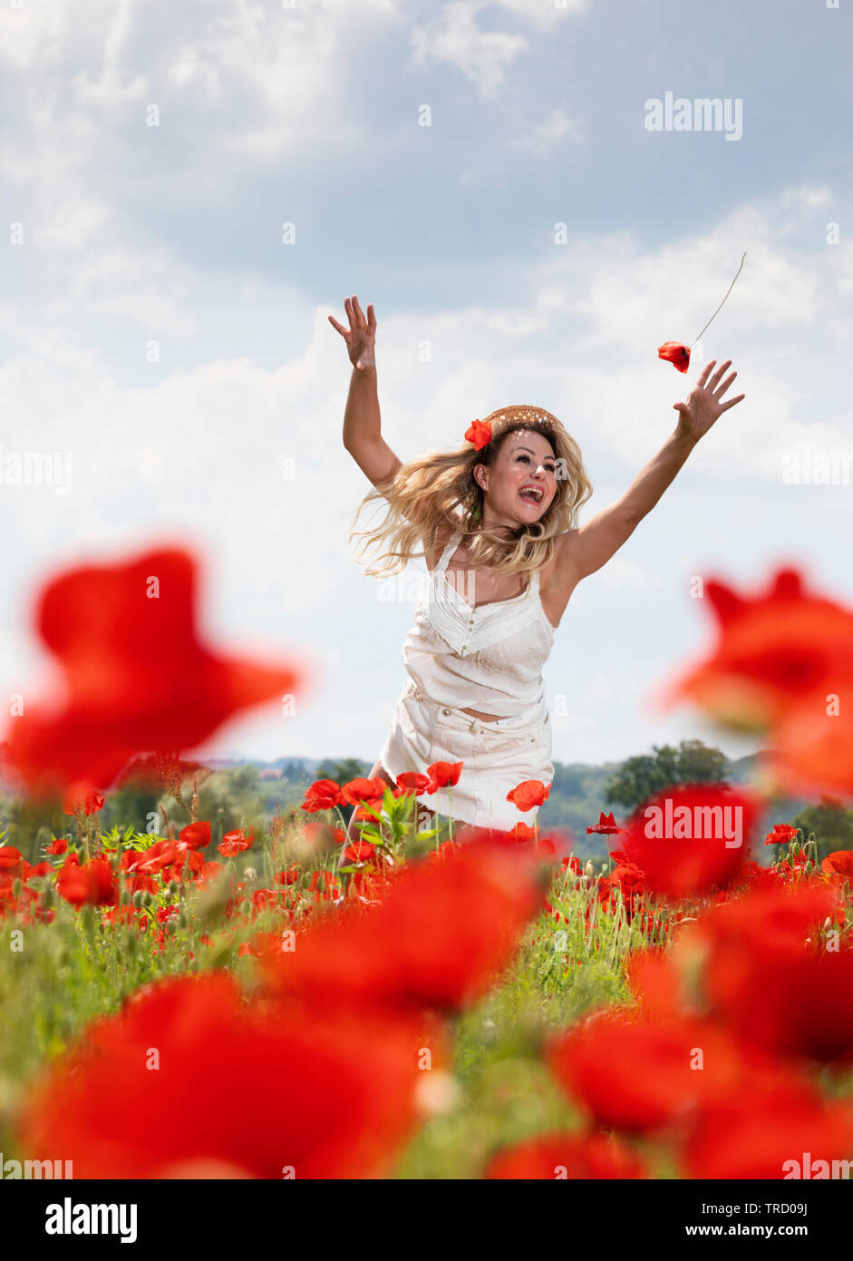 Young woman catch poppy flower in the air Stock Photo